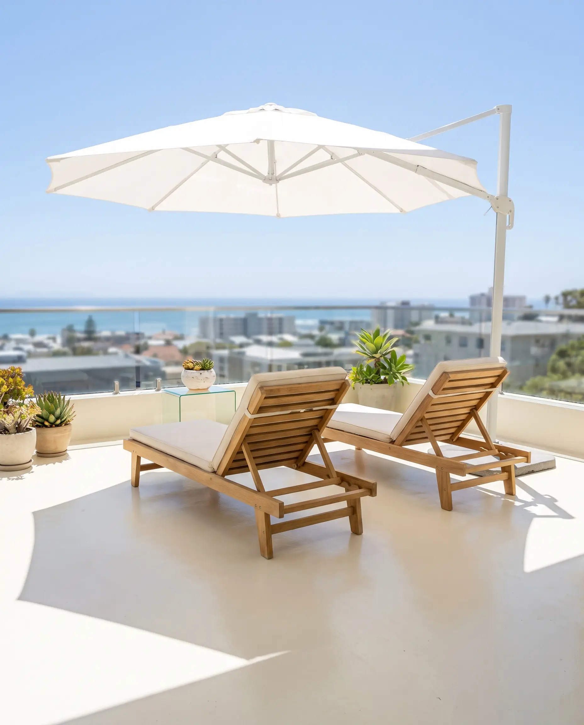 Slatted natural oak loungers and a structural minimalist shade umbrella rest on a pristine low-traffic balcony coated in Ultra Pure White floor paint.