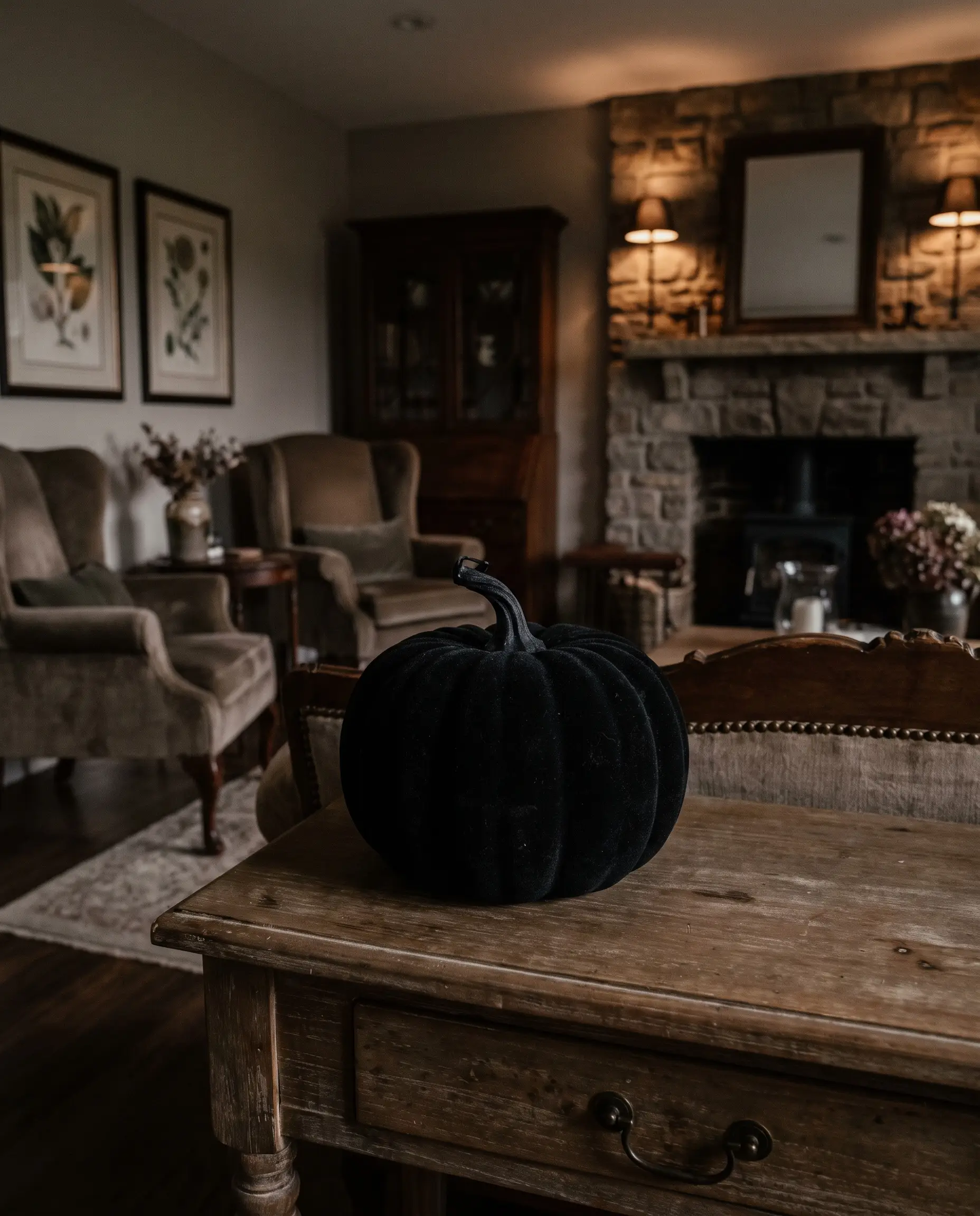 An ultra-matte, light-absorbing black velvet flocked pumpkin creates a striking Victorian gothic contrast against a standard wooden console table in a lived-in space.