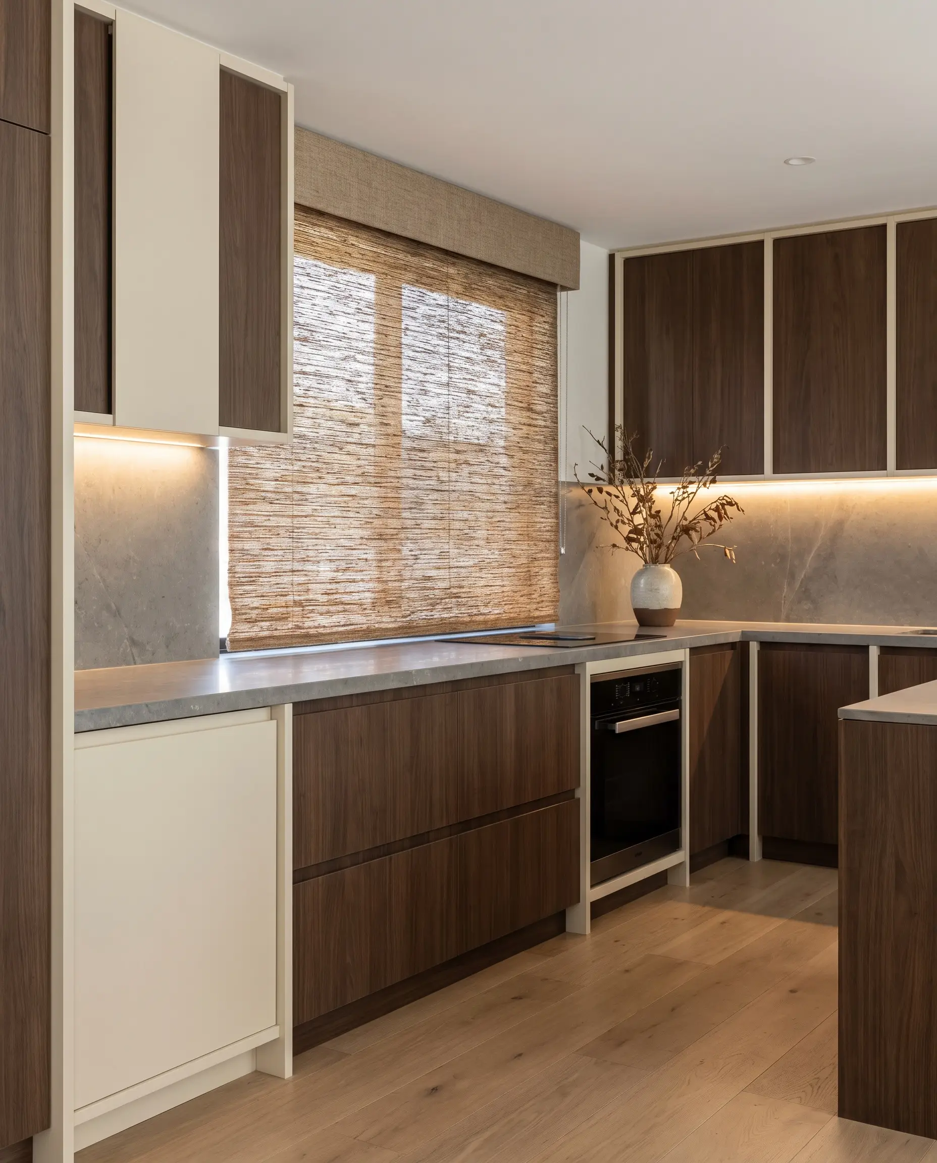 Natural woven matchstick and reed shades with an integrated valance headrail introduce organic texture against flat-panel cabinets painted in Dover White and stone countertops.