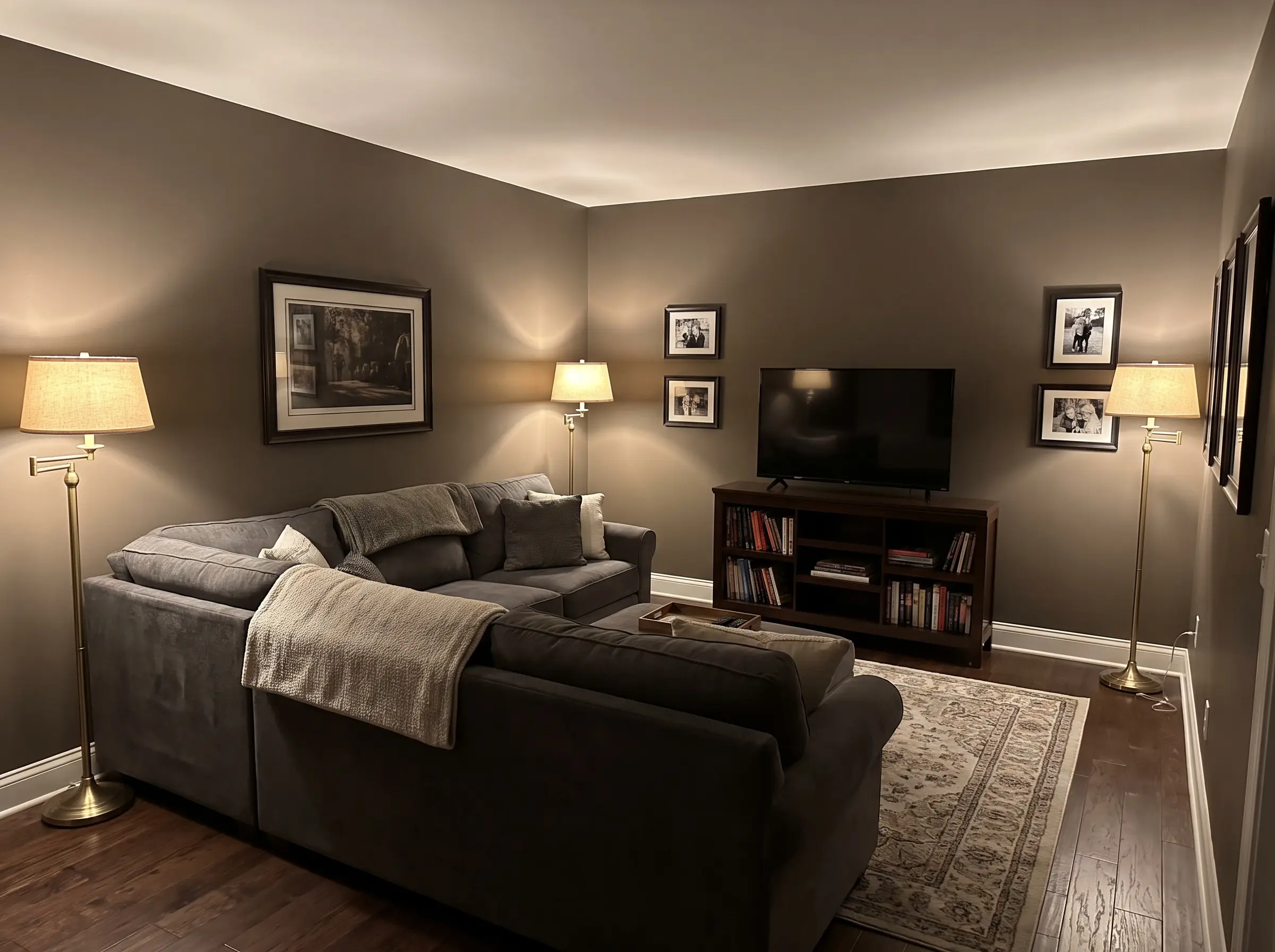 A lived-in charcoal fabric sectional and dark wood media console furnish an intimate media room painted in rich brown-taupe gray.
