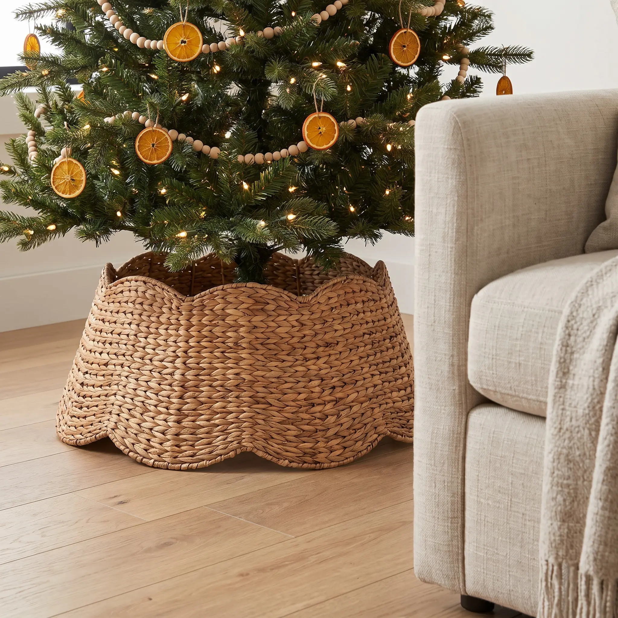 An architectural scalloped rattan wicker tree collar woven from water hyacinth completely conceals the metal stand of this tailored 2026 Christmas tree decor.