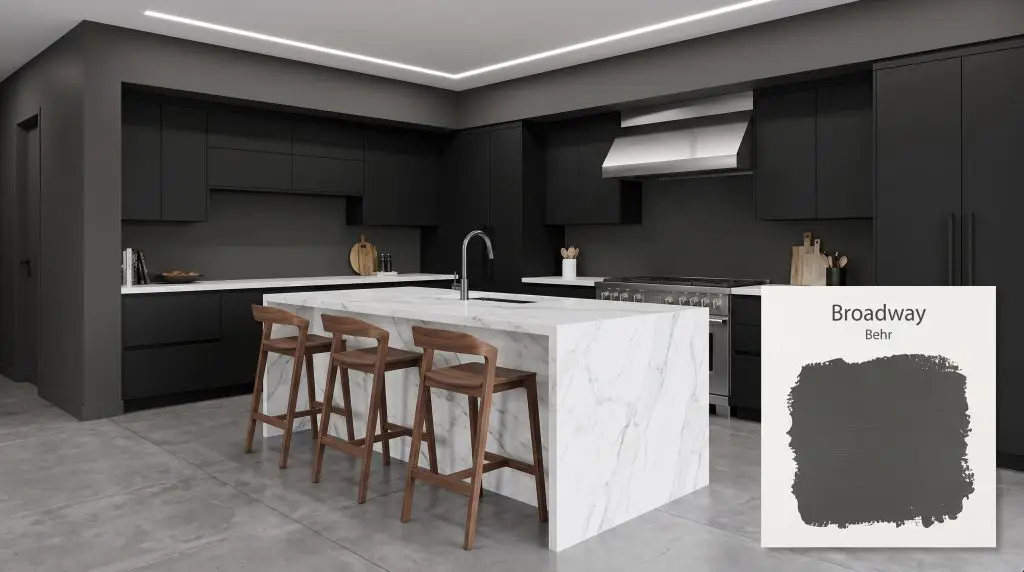 Sleek recessed lighting illuminates matte black cabinetry, a white waterfall marble island, and warm walnut bar stools against a dark Behr Broadway (Hex #434442) wall.
