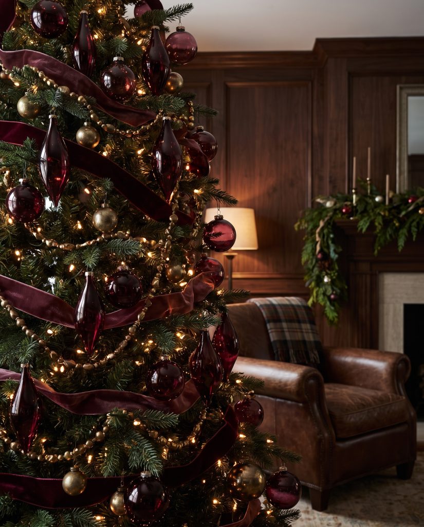 Deep Sherwin-Williams Carnelian and Farrow & Ball Brinjal blown glass ornaments hang beside unlacquered brass accents and cotton velvet ribbons in this 2026 Christmas tree decor.