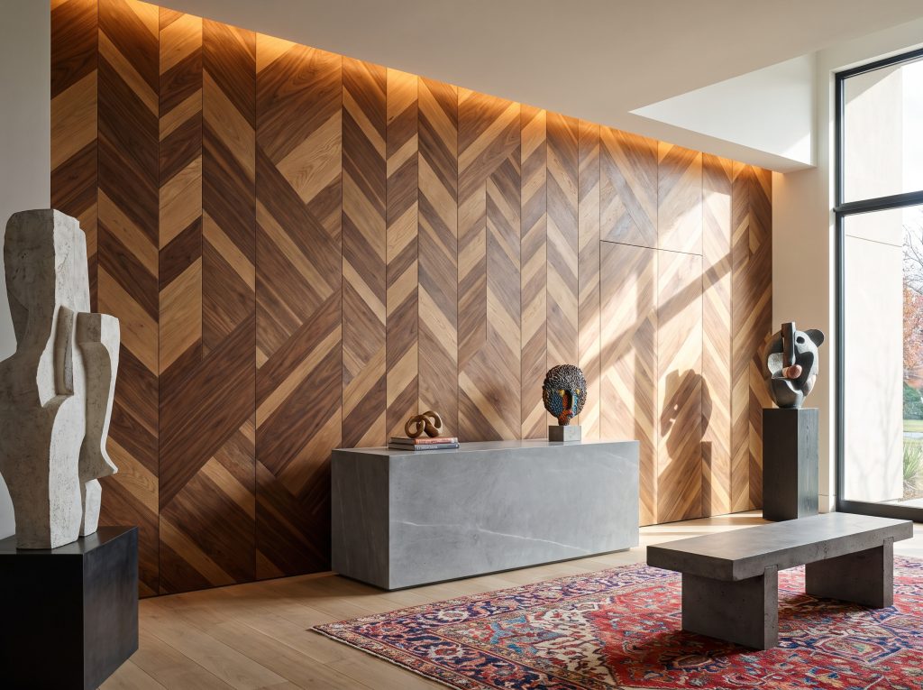 Mixed-tone walnut and oak veneer tiles laid in an asymmetrical chevron pattern provide a kinetic backdrop for a smooth monolithic stone console table.