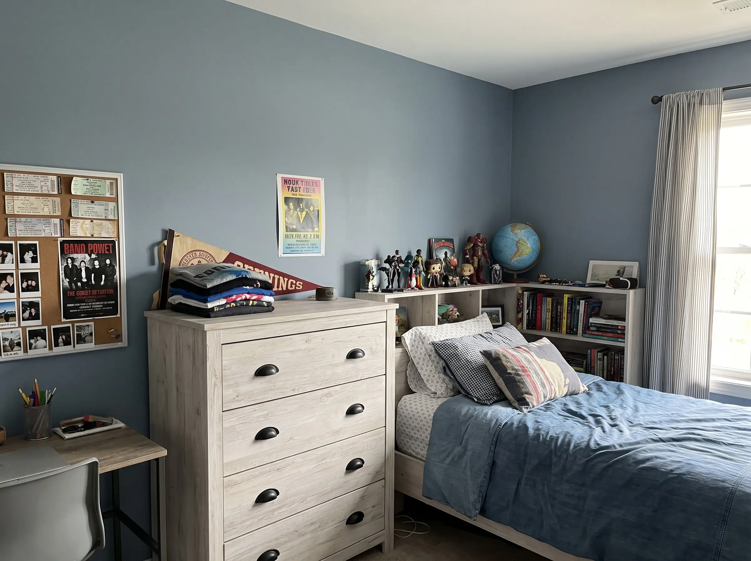 Muted slate blue paint colors for boys room walls complement a whitewashed wood dresser accented with matte black drawer pulls and teenage memorabilia.