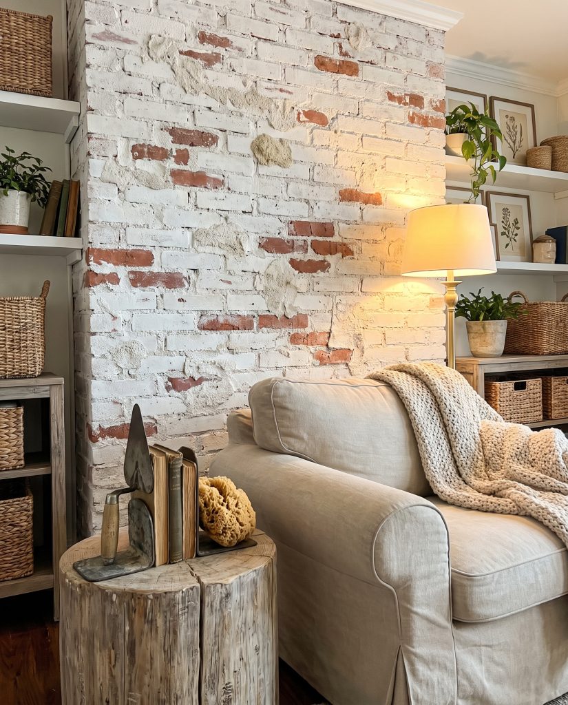 Heavy white Portland cement coats a rugged masonry surface behind a slipcovered linen armchair, rustic wooden side table, and a heavy-duty masonry trowel.