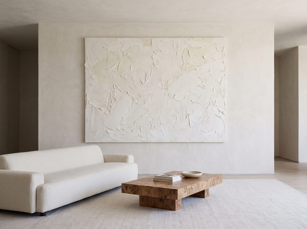 A modern minimalist living room featuring a massive unframed abstract canvas hung on a Roman clay wall above a low-profile boucle sofa and burl wood coffee table.
