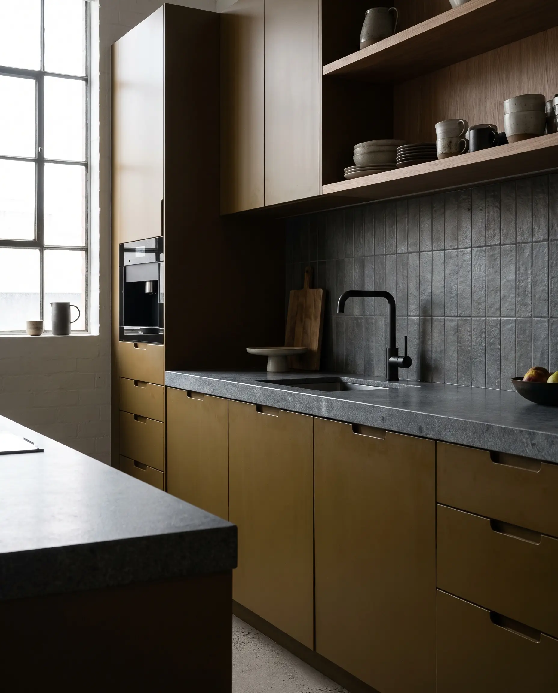 Cool slate gray stone countertops and a matte gray backsplash neutralize intense muddy ochre cabinetry in this sophisticated urban contemporary yellow and gray kitchen.
