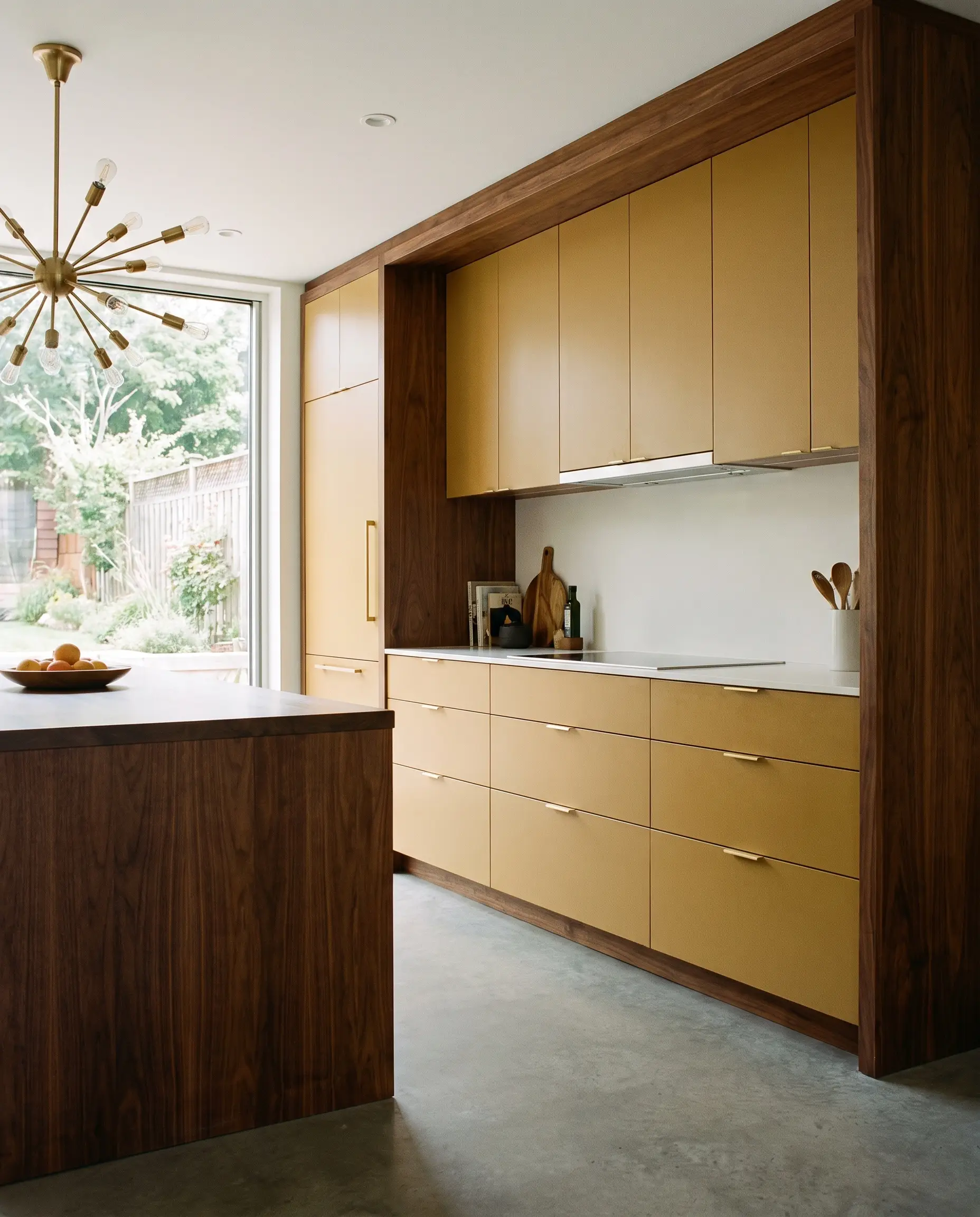 Farrow & Ball India Yellow flat-panel cabinetry contrasts sharply against solid dark walnut framing and minimalist integrated hardware in a mid-century modern layout.