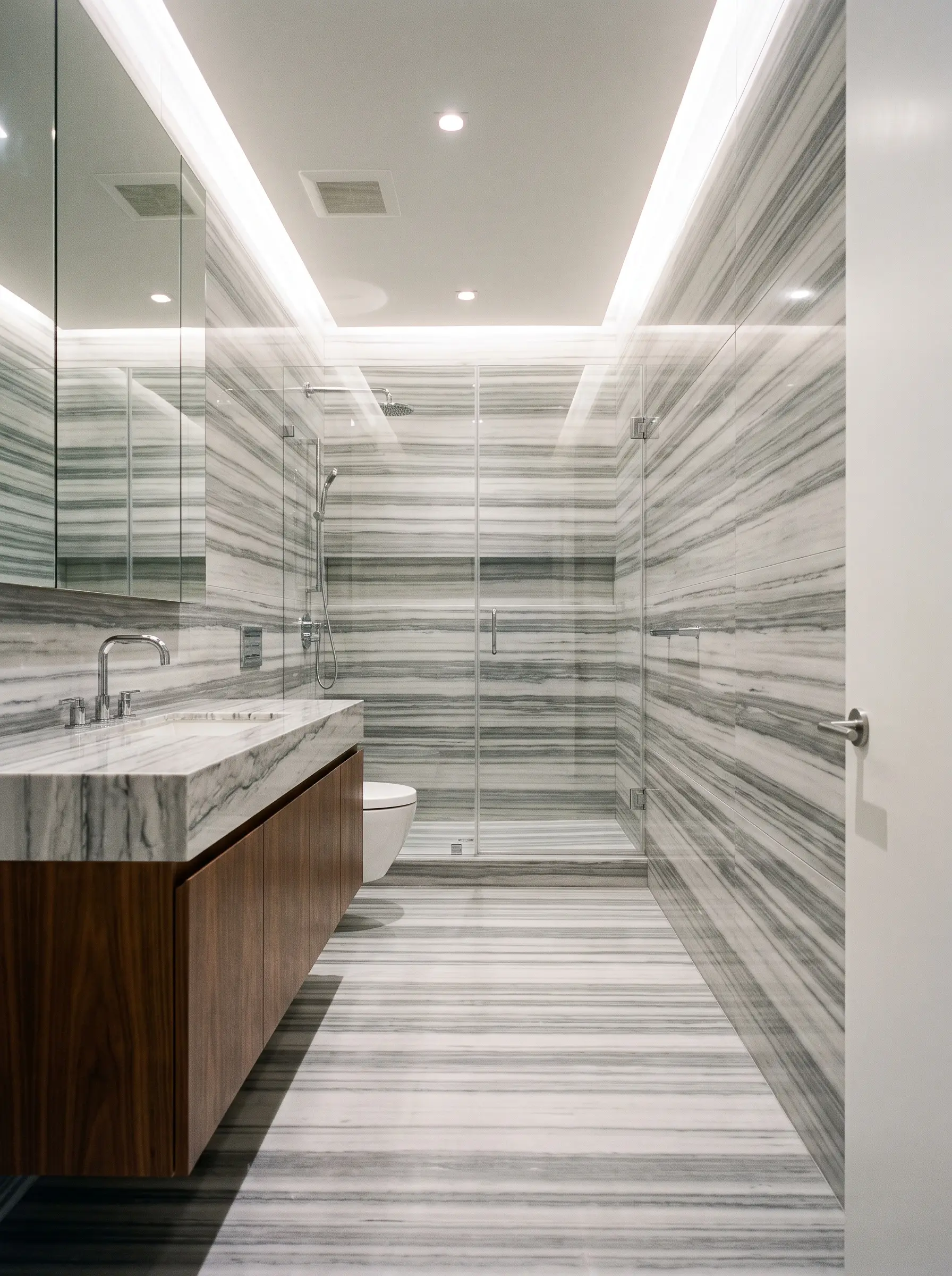 Dominant linear veining runs horizontally across Striato Olimpico marble floor tiles, visually expanding a narrow space featuring a floating walnut vanity and frameless glass shower enclosure.