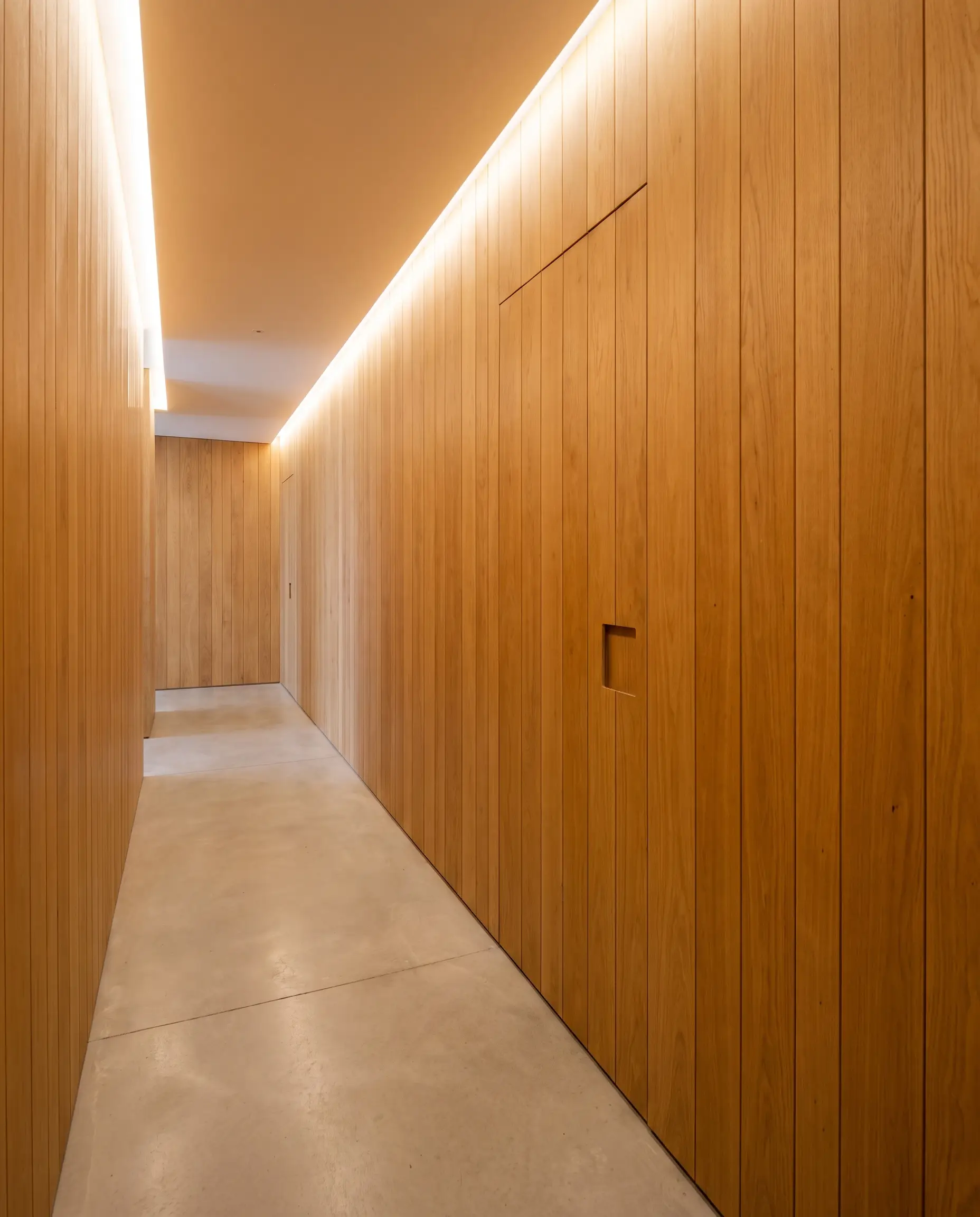 Precision-milled vertical tongue and groove oak planks form a continuous architectural surface that seamlessly conceals a flush jib door with a recessed finger pull.