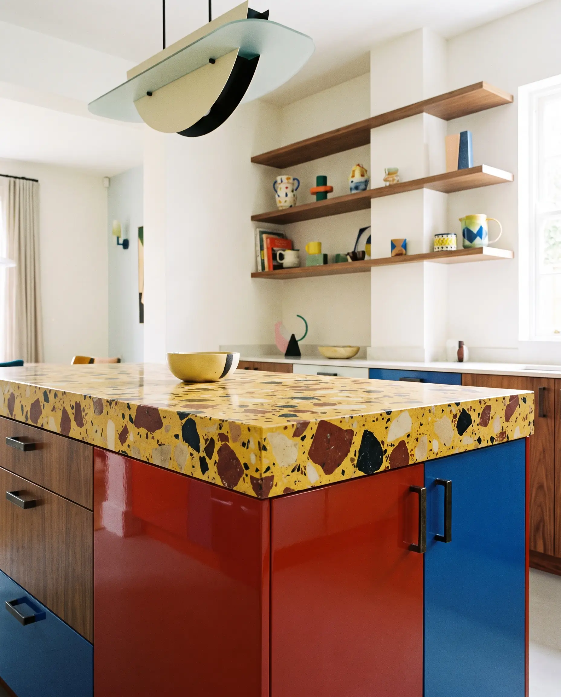 A vibrant yellow-based terrazzo slab countertop with deep rust and black flecks rests above cabinetry fitted with dark hardware in an Italian-inspired space.