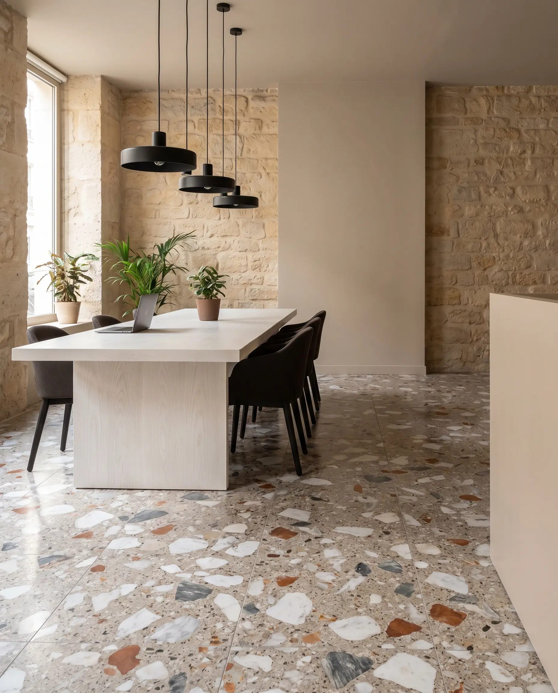 A solid white ash collaborative table rests on poured terrazzo flooring with large-scale marble aggregate against Sherwin-Williams Accessible Beige limestone walls.