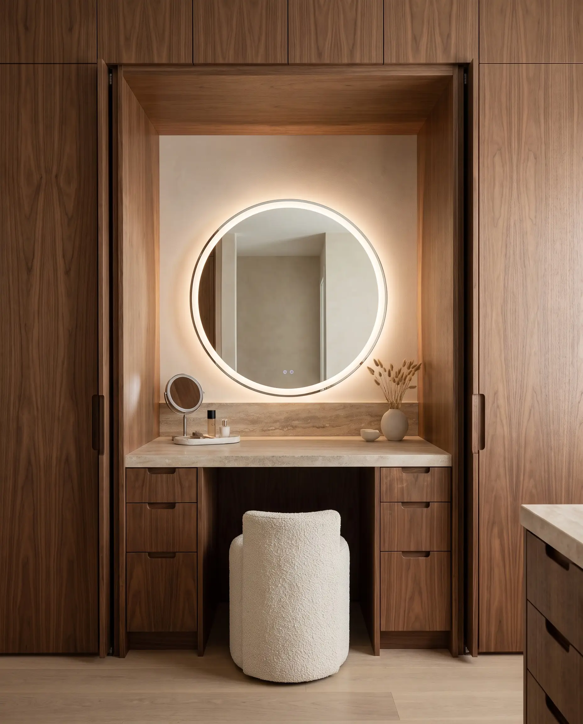 A dedicated seated vanity station with retractable pocket doors and a plush stool highlights practical 2027 closet and wardrobe design trends.