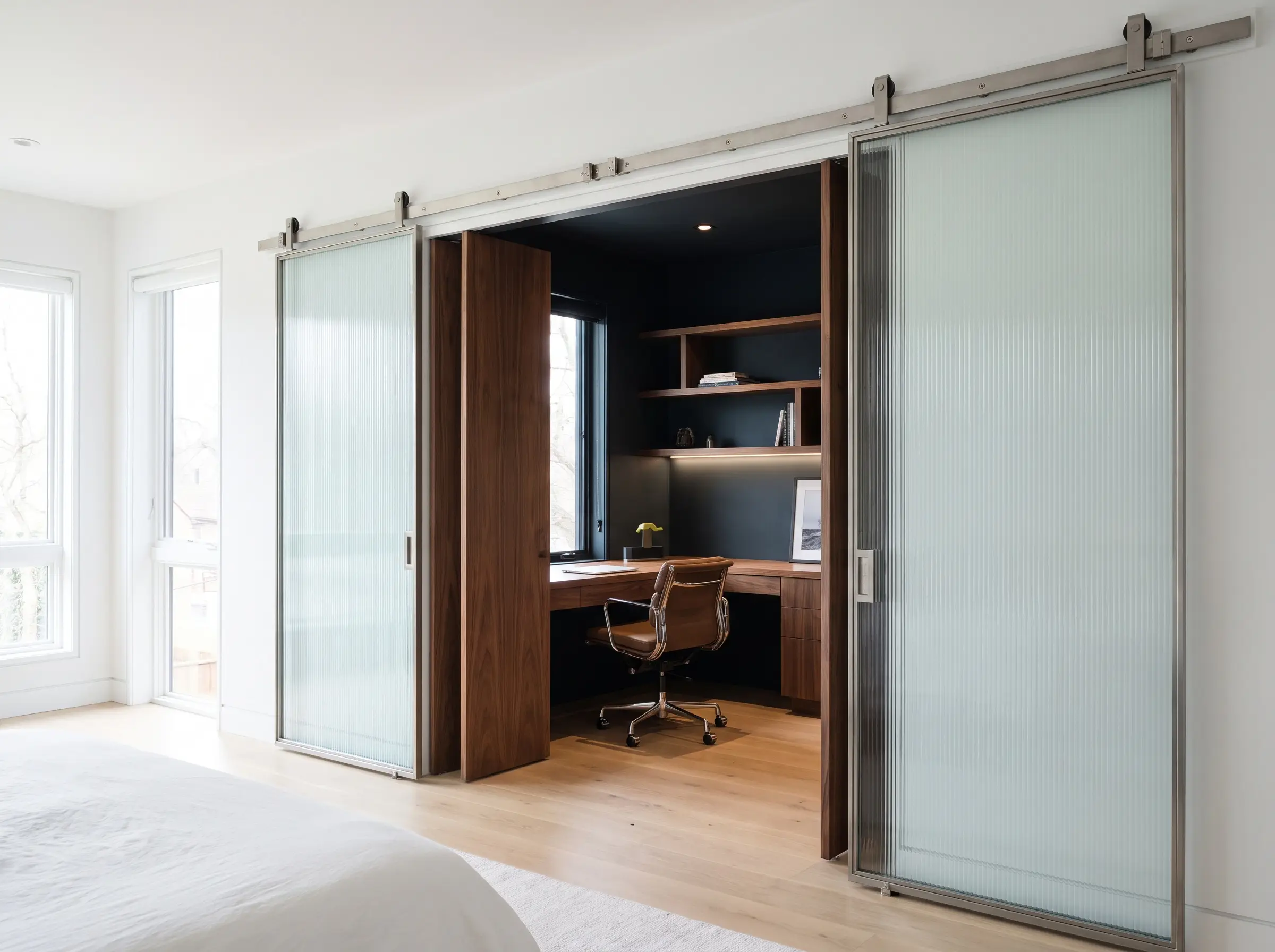 Portes à galandage en verre cannelé s'ouvrant sur un bureau intégré en noyer, illustrant l'optimisation des petits espaces de travail en 2027.