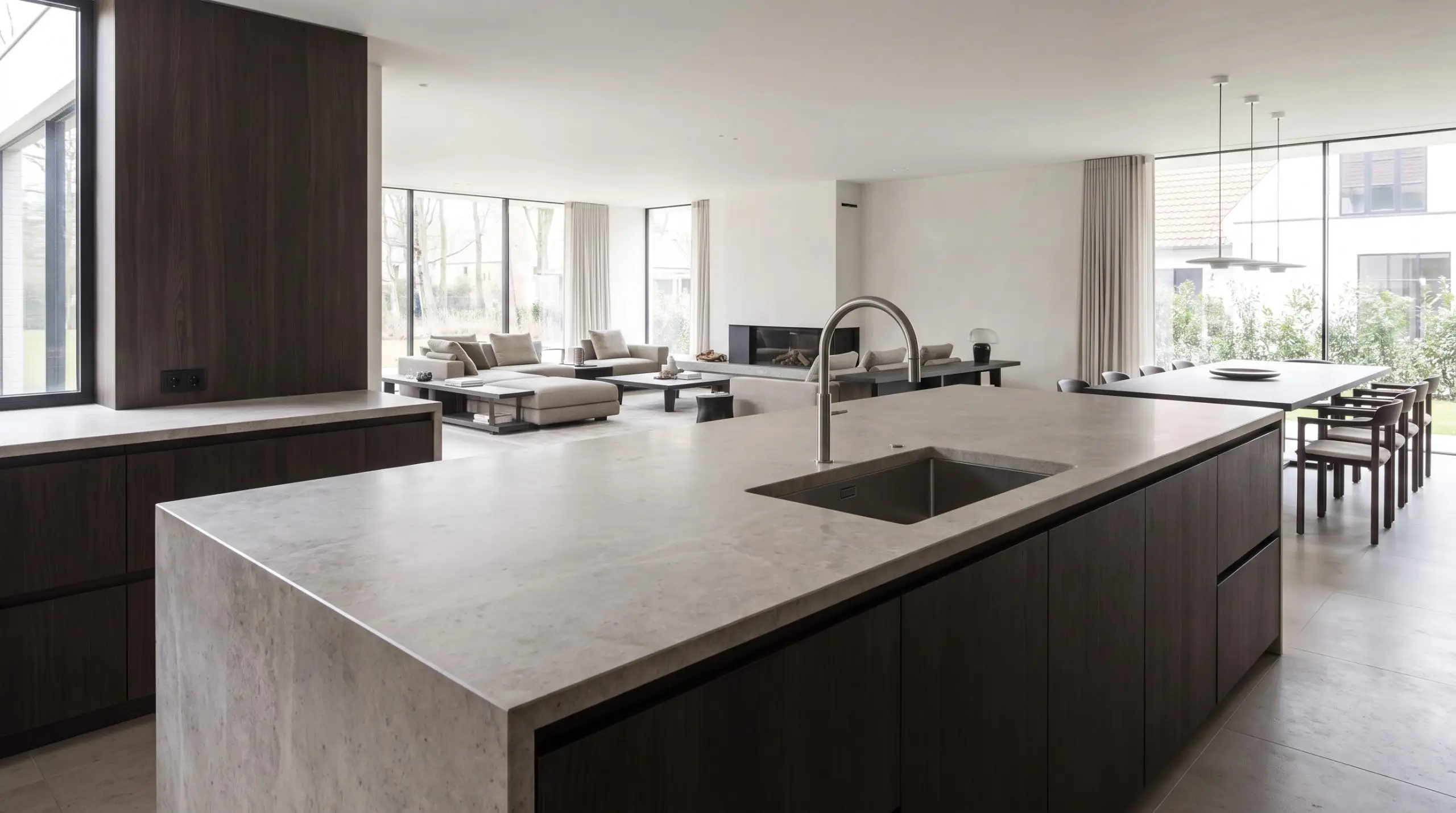 A sleek low-profile retractable faucet and under-mounted stainless basin showcase kitchen faucet and sink trends 2027 on a minimalist primary entertainment island.