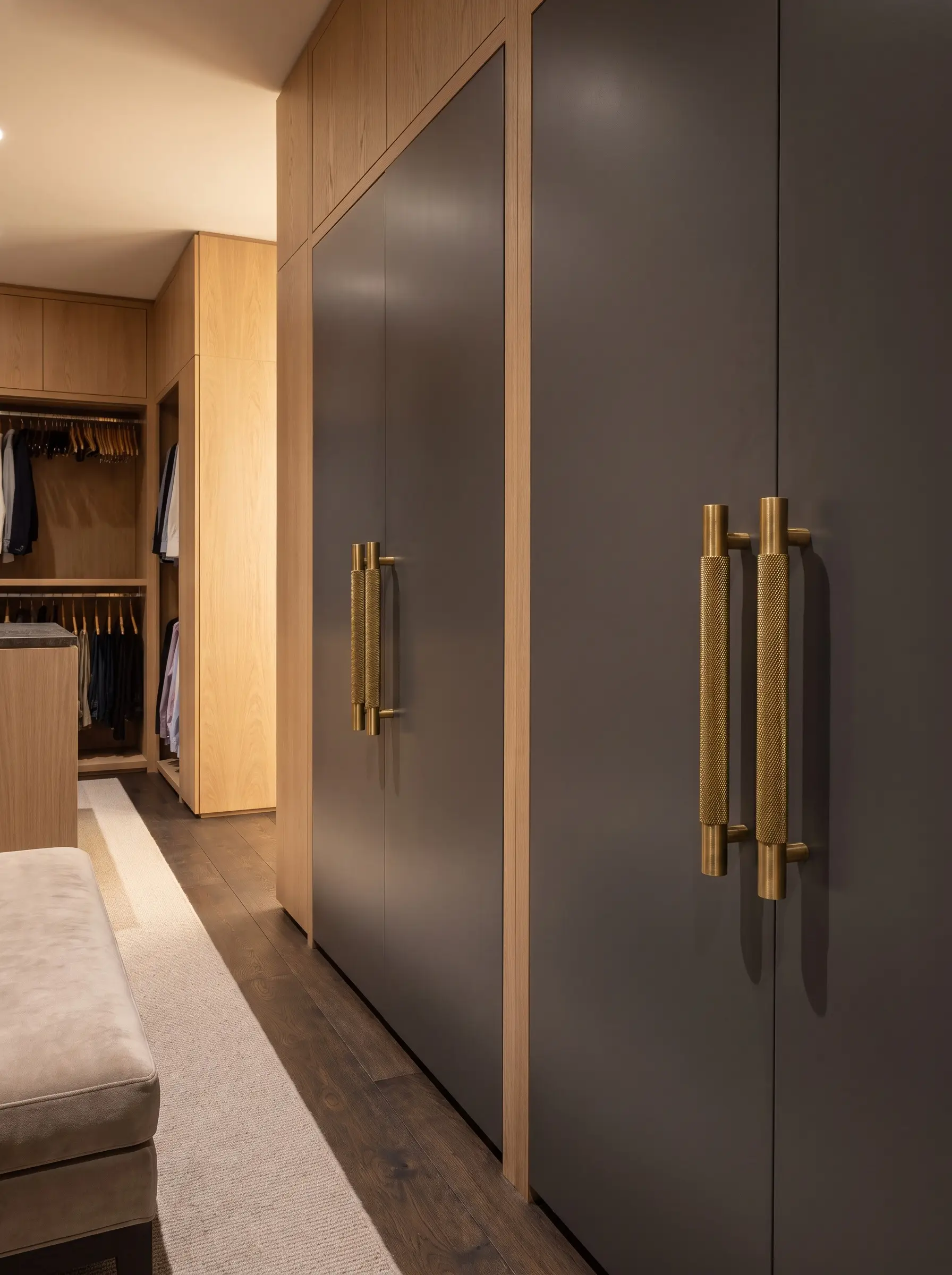 Heavyweight knurled brass bar pulls are mounted on solid slab wardrobe doors surrounded by rift-sawn wood cabinetry.