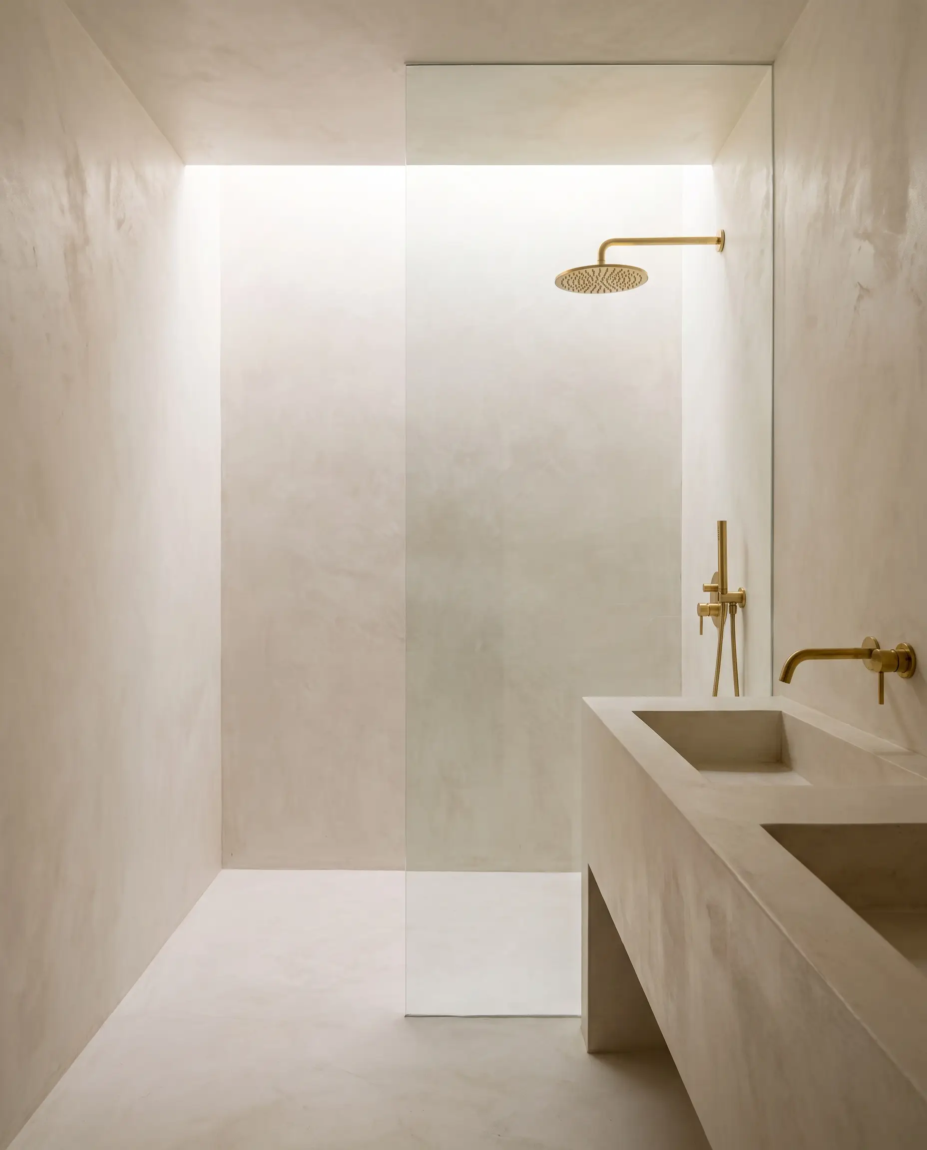 A continuous polymer-modified microcement coating wraps the walls, floor, and integrated vanity basin of this walk-in shower reflecting bathroom wall covering trends 2027.