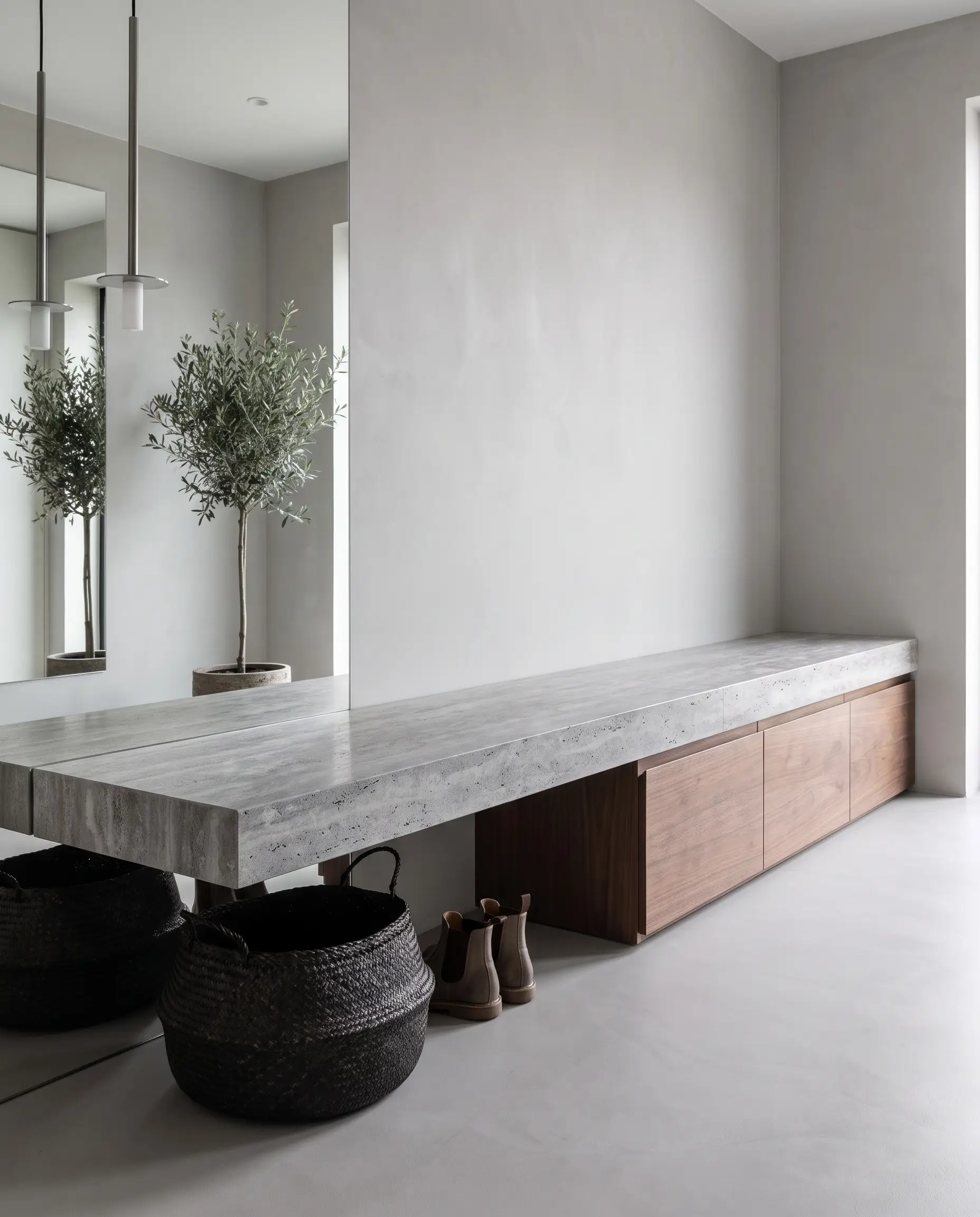 A thick silver travertine slab projects from a smooth plaster wall above under-mounted matte walnut drawers and a seamless micro-cement floor.