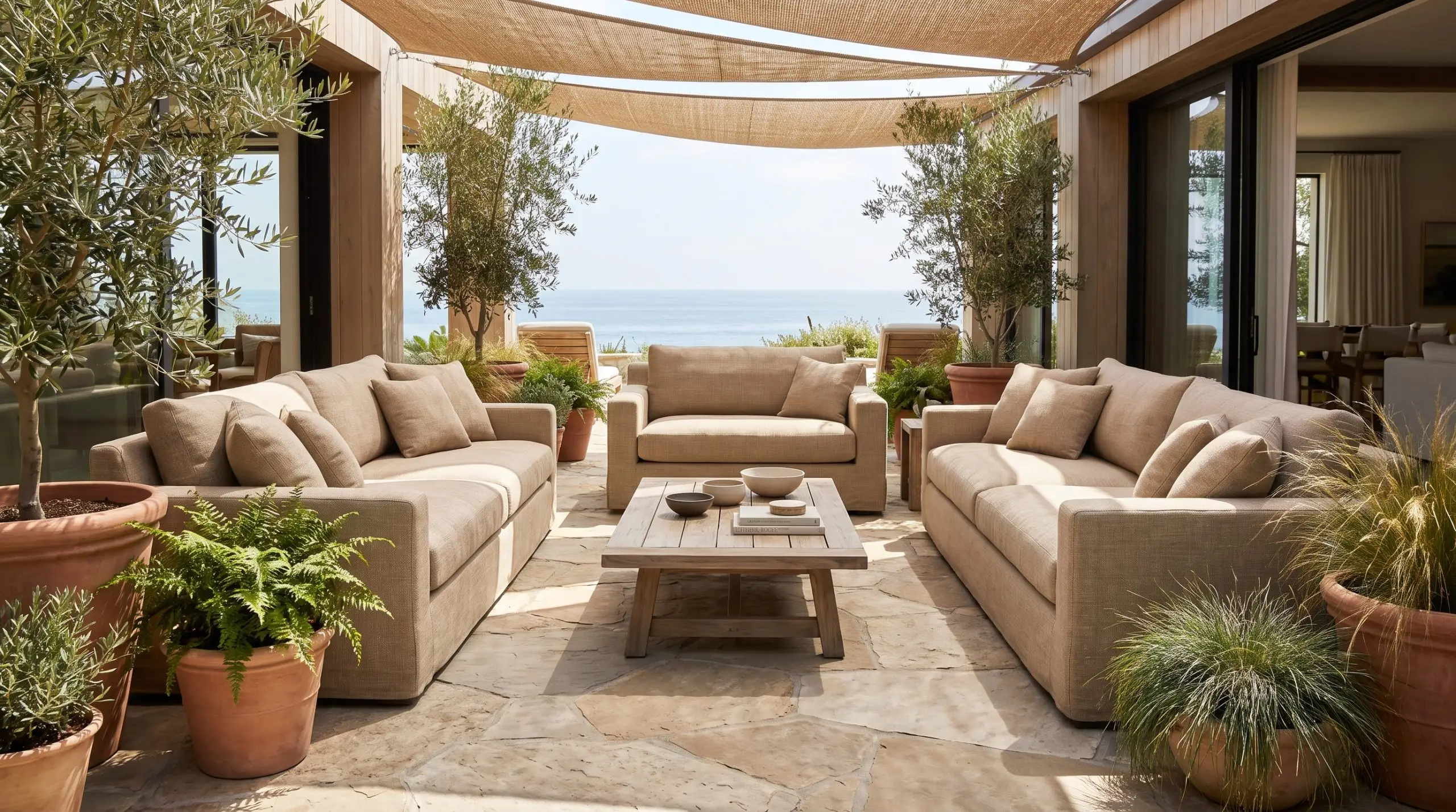Mobilier de jardin haut de gamme revêtu de polyester technique issu du recyclage horizontal sur des dalles en pierre naturelle autour d'une table en teck.