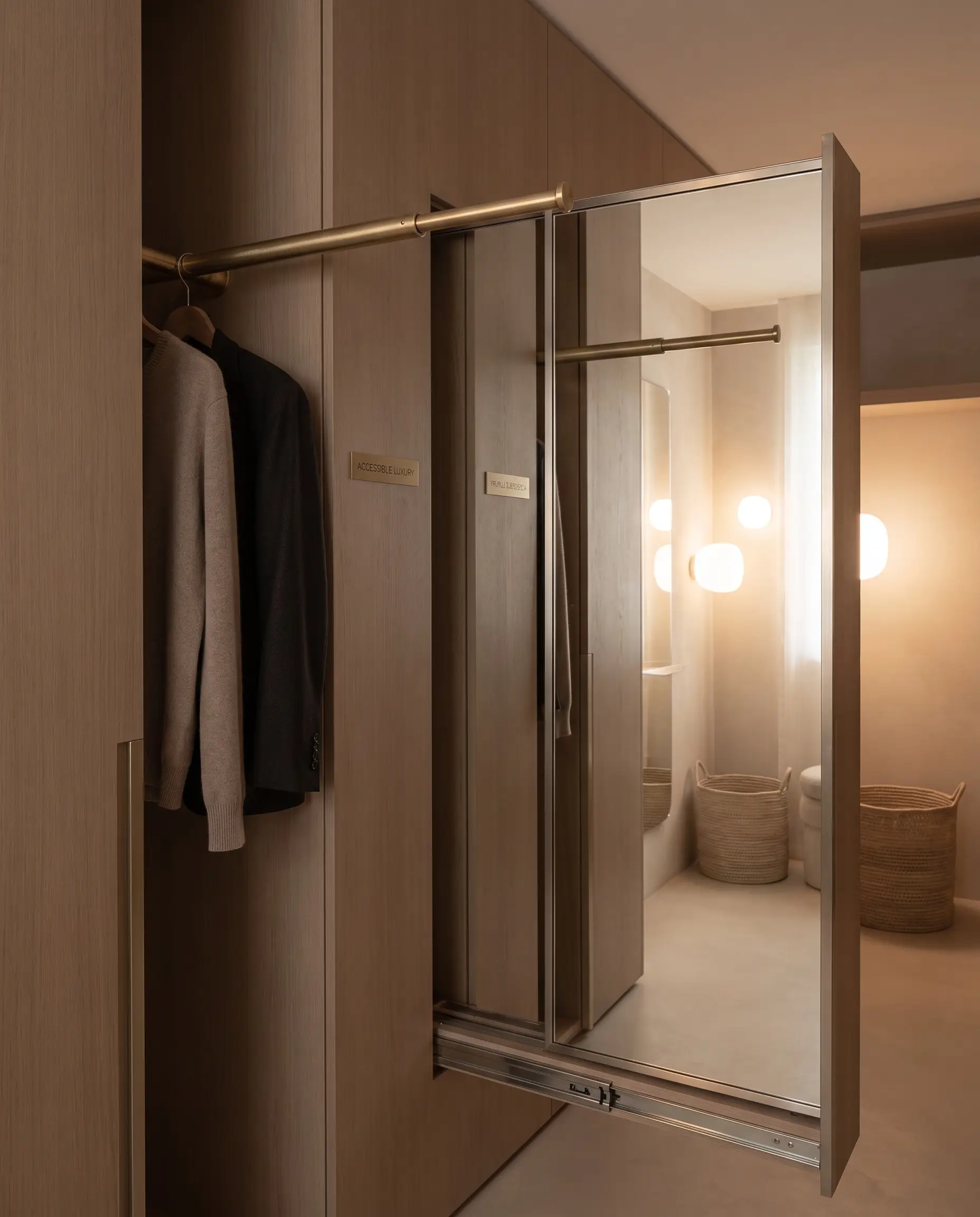 A heavy-duty telescopic valet rod in brushed brass pairs with a hidden pull-out full-length mirror gliding from a vertical cabinetry gap.