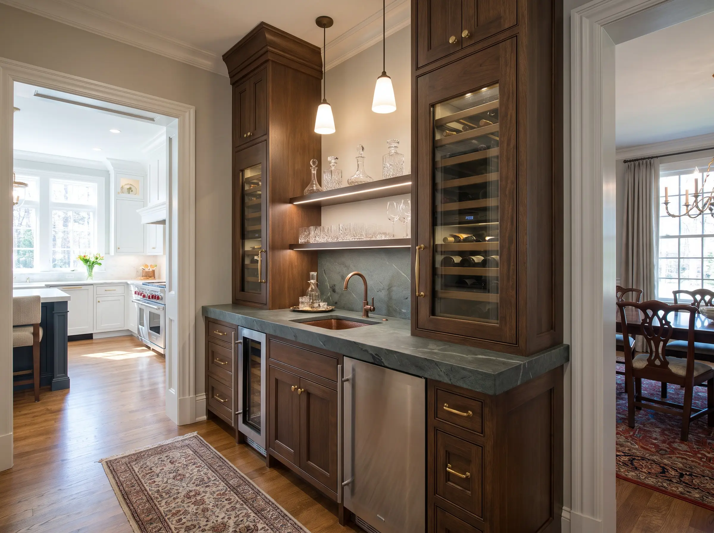 Integrated refrigerated columns and durable natural stone countertops equip this dedicated wet bar bridging a chef's kitchen and a formal dining room.