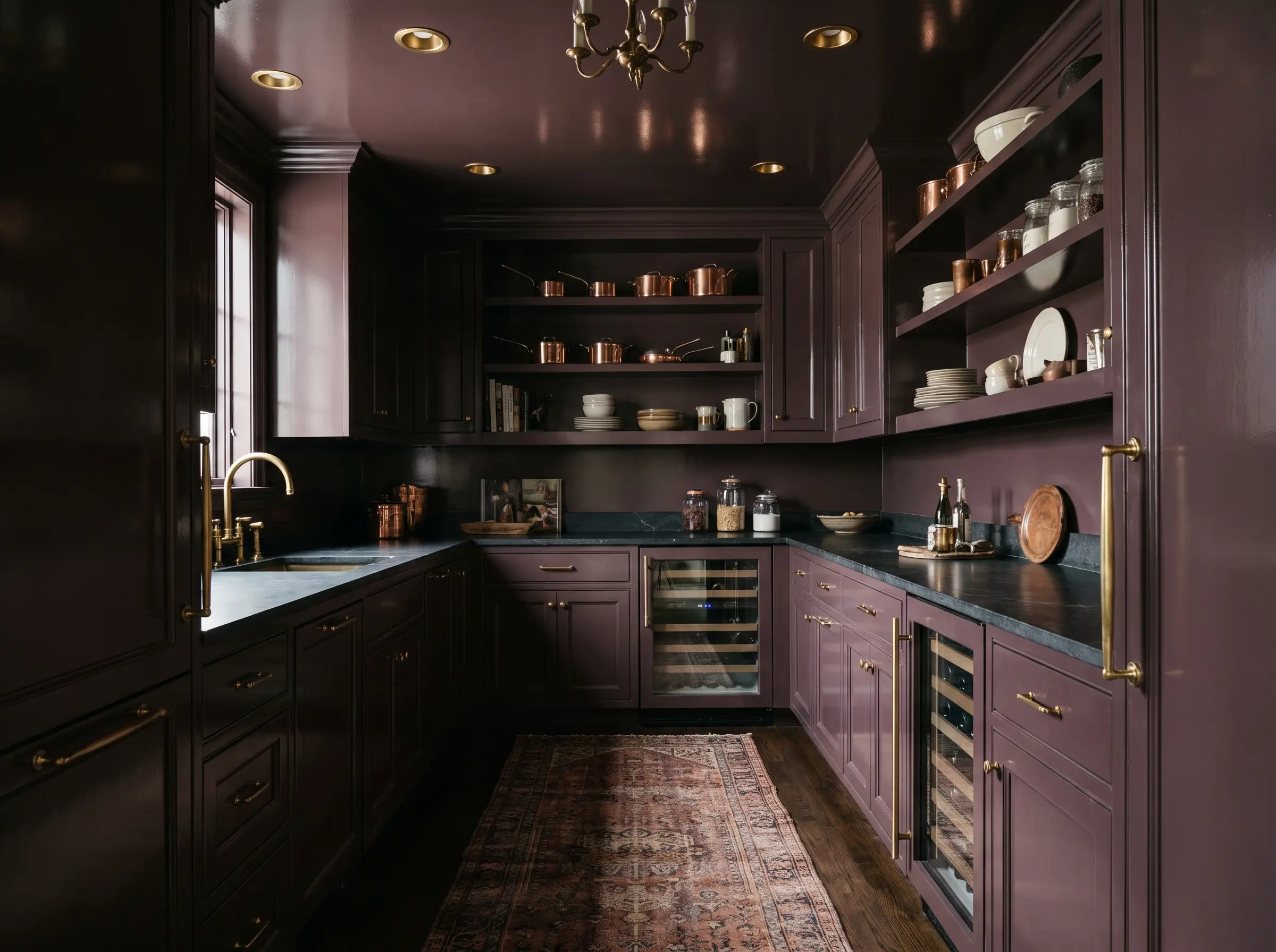 Walk in pantry and scullery trends highlight a jewel box space with cabinetry and walls color-drenched in dark aubergine Farrow and Ball Brinjal paint featuring brass hardware.