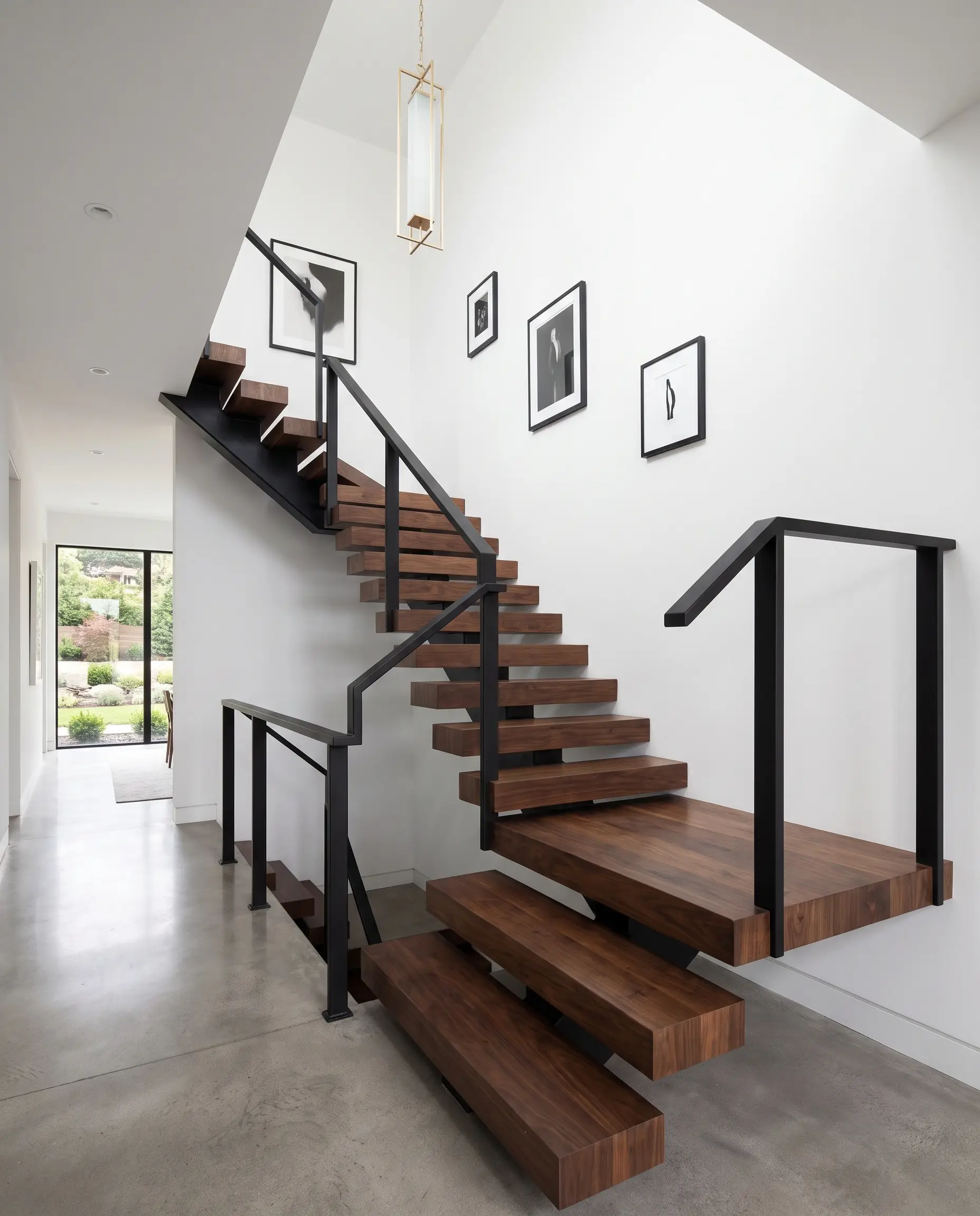 Solid warm walnut stair treads and graphic matte black powder-coated steel stanchions frame a luxurious residential hallway showcasing 2027 staircase and railing trends.